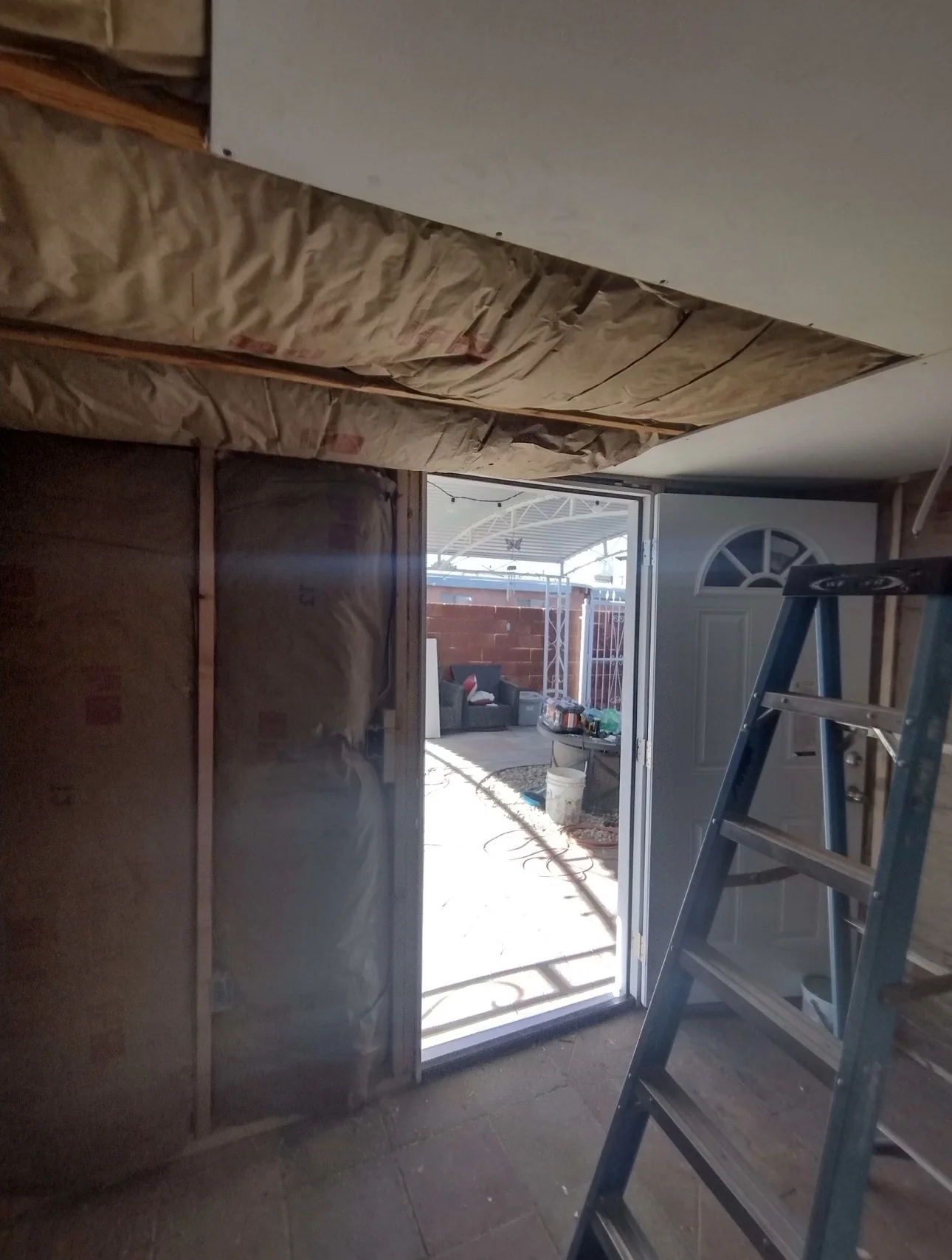 Interior remodeling project with ceiling opened up, insulation visible, and entry area under renovation